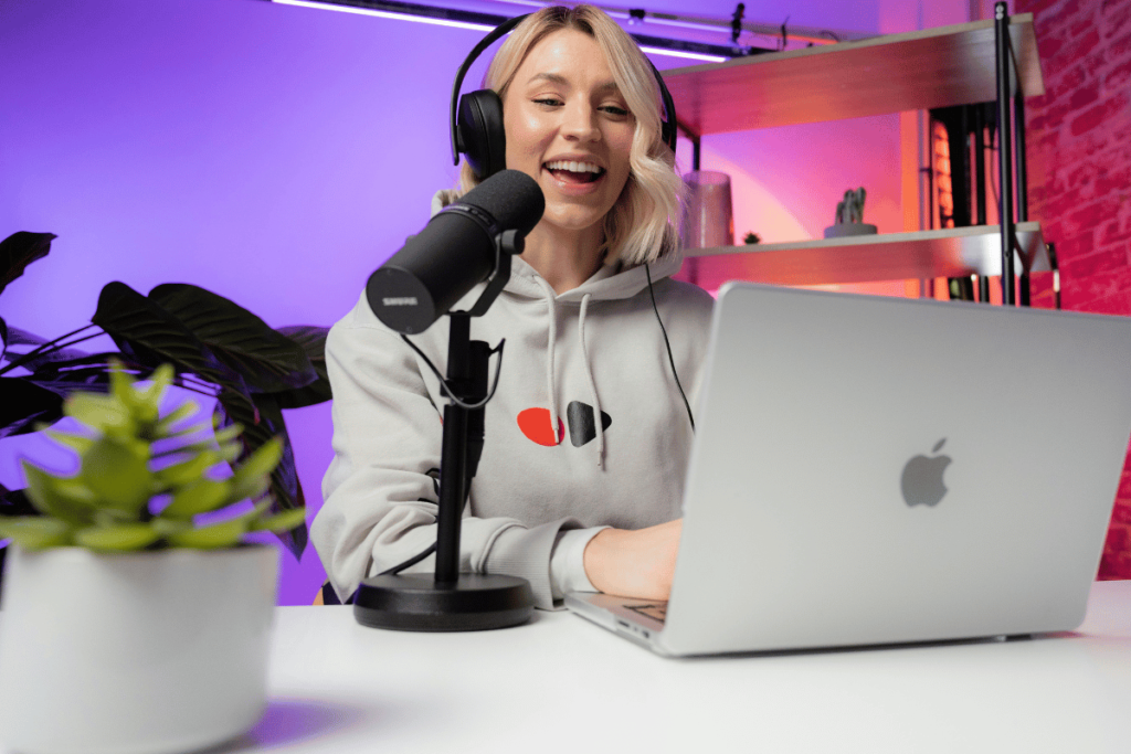 Happy woman podcasting with mic and laptop.