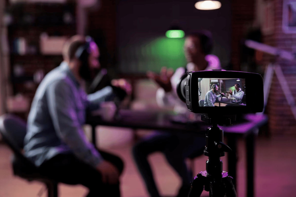Two people sitting at a table with a camera in front of them.