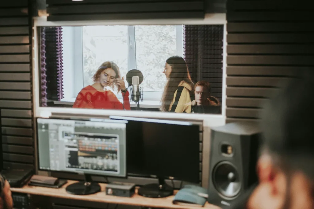 Group recording vocals in professional soundproof studio booth.