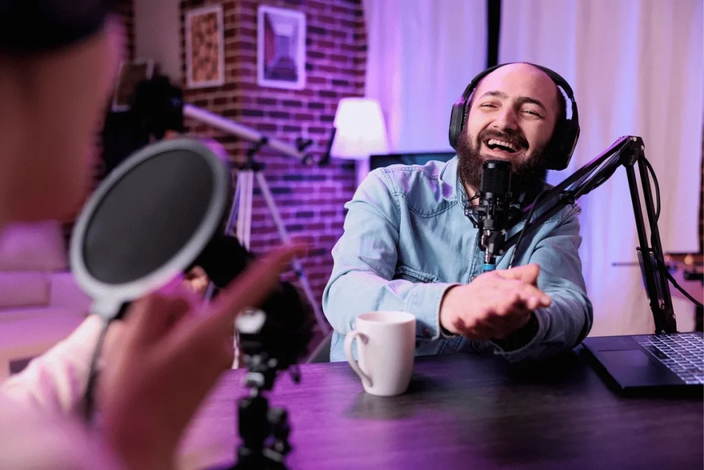 Man laughing during podcast recording session with professional microphone.