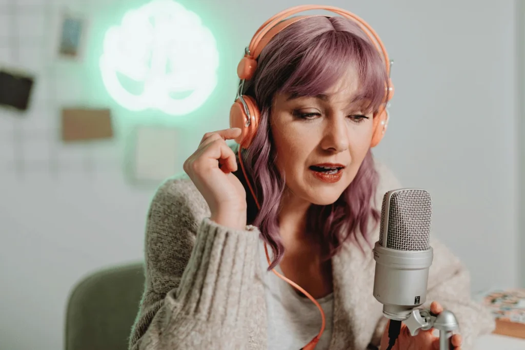 Woman with purple hair recording podcast using professional microphone.