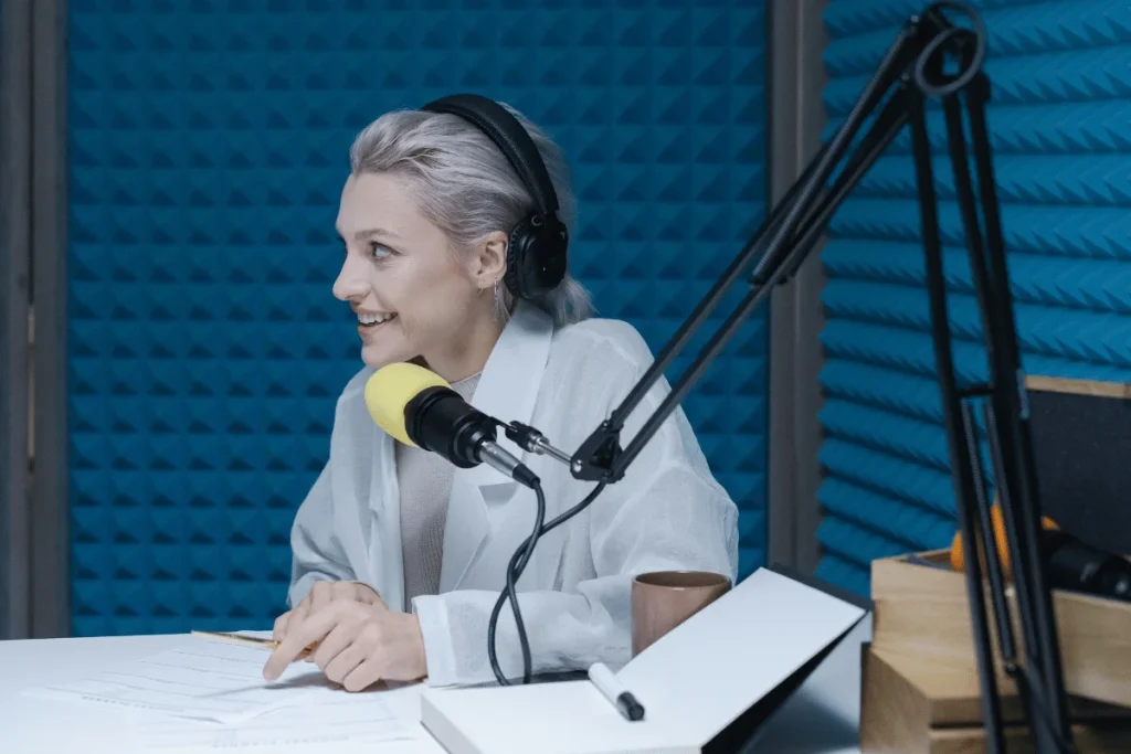 Woman podcasting in soundproof studio with yellow mic.