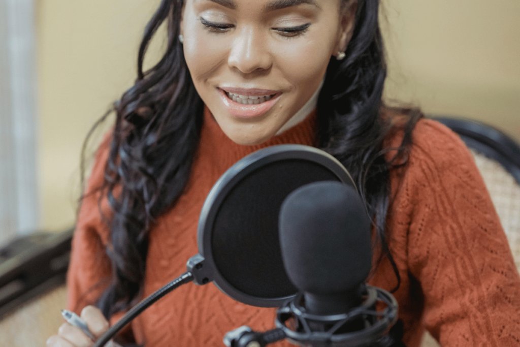 Smiling woman recording with a professional microphone, podcasting or singing at home.