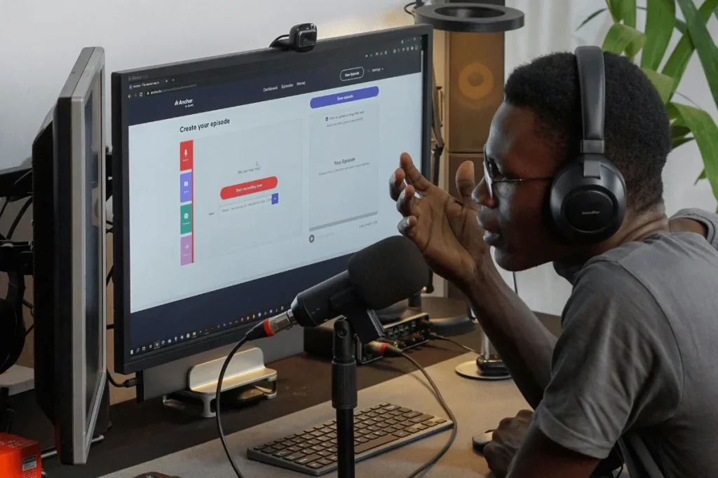 Podcaster speaking into a microphone while wearing headphones.