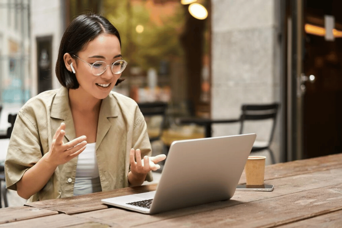 A cheerful person sitting at a table with a laptop.