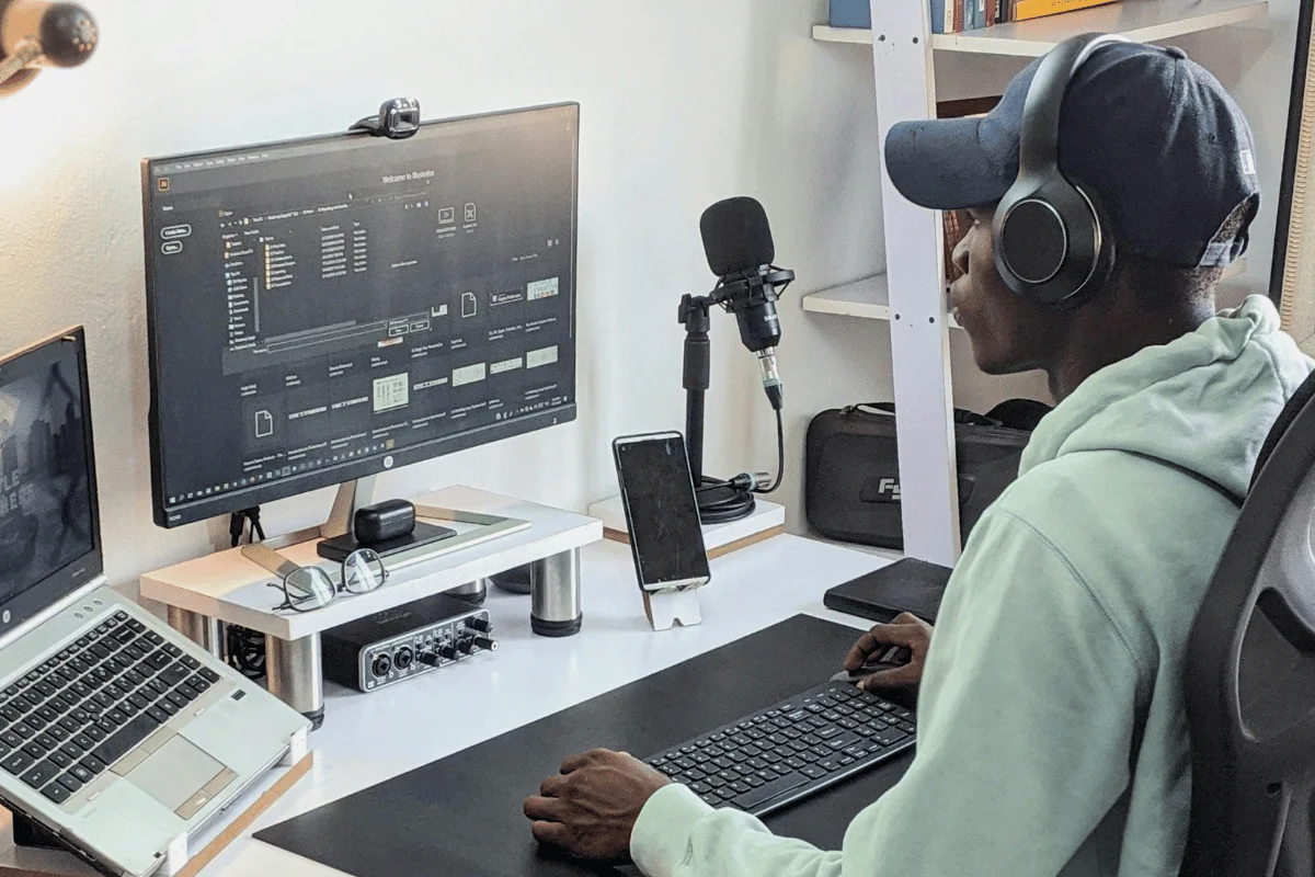 Focused male audio engineer adjusting settings on his computer in a well-equipped podcast studio.