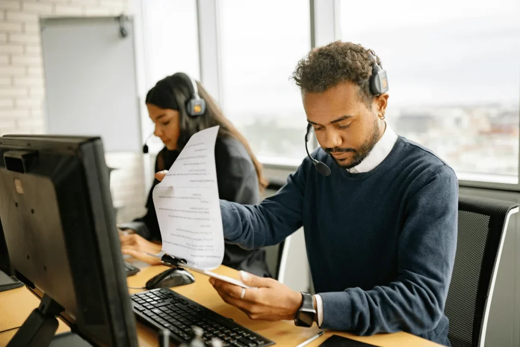 Office workers with headsets concentrating on their computers in a bright workspace.