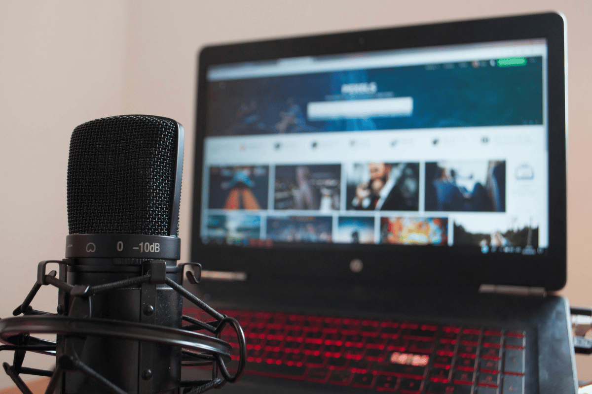 Podcasting microphone set up with a laptop displaying a video platform.