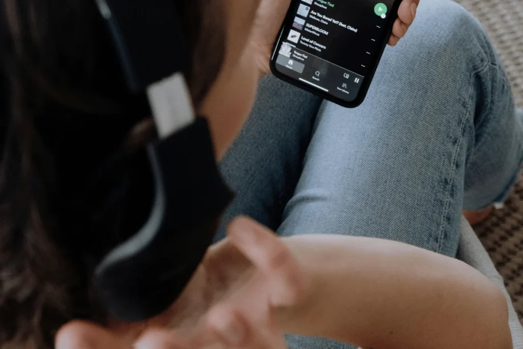 Close-up of a person's hand holding phone with a visible music playlist on screen.