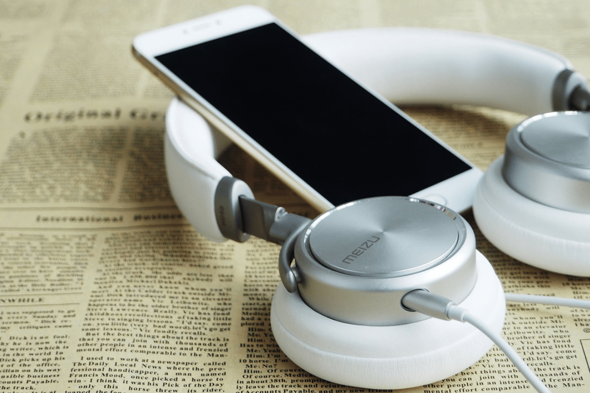 White headphones and smartphone on a newspaper background.