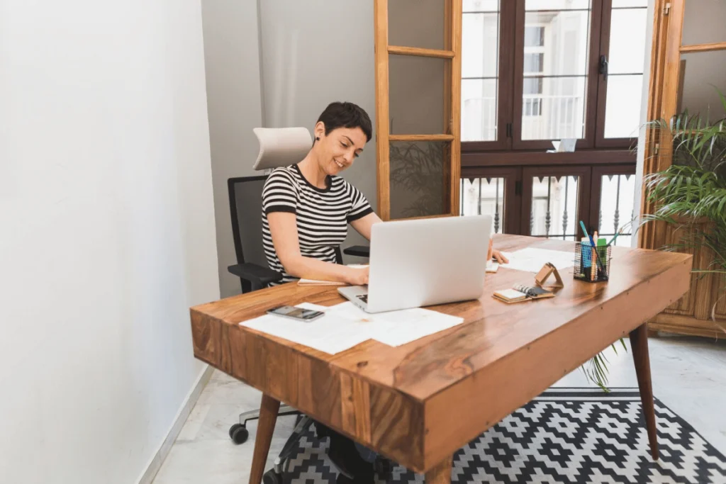 Smiling woman working on her laptop in a bright home office.