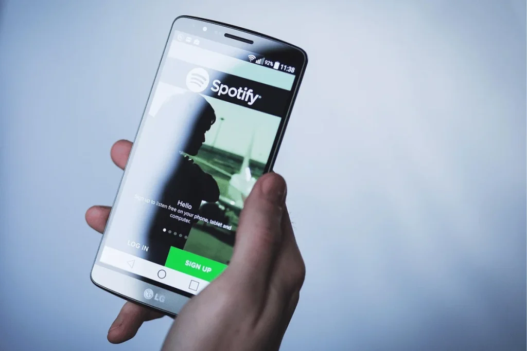 Hand holding smartphone with Spotify login screen open.