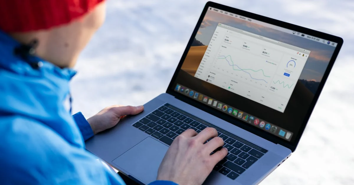 Person in red beanie typing on laptop with B2B podcast planning interface displayed on screen outdoors.