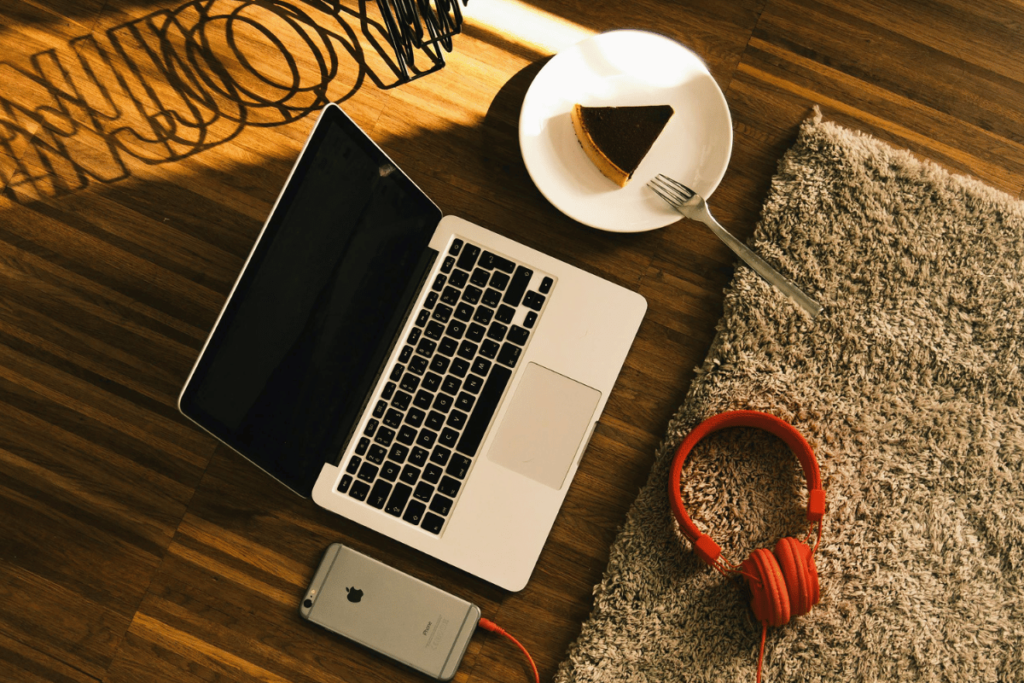 Comfortable and inviting work area with a laptop, phone, and bright red headphones.