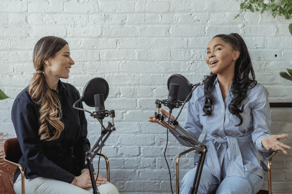 Female podcast hosts engaging in a lively discussion in a studio setting.