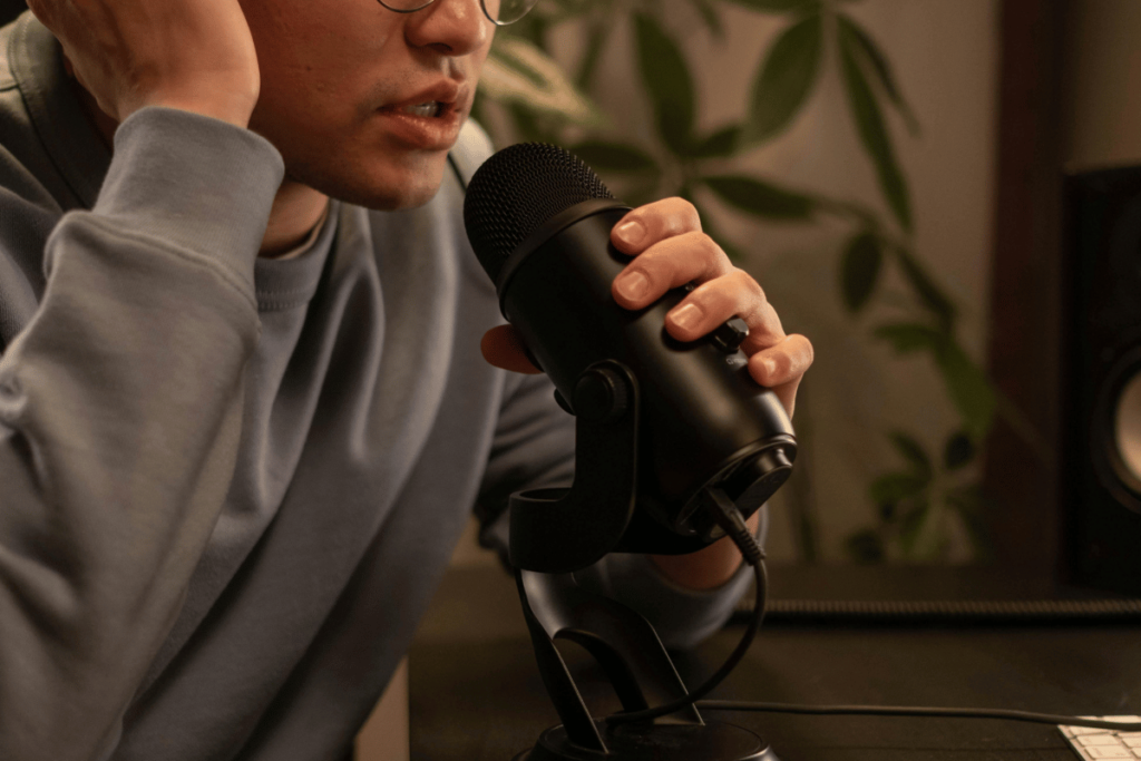 Close-up of a man speaking into a studio microphone with a reflective posture.