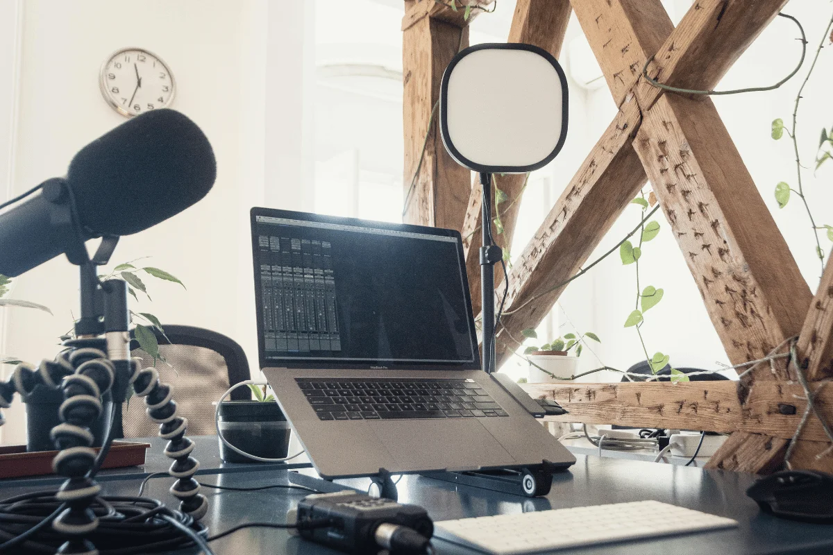 Podcasting setup with mic, laptop, and lighting.