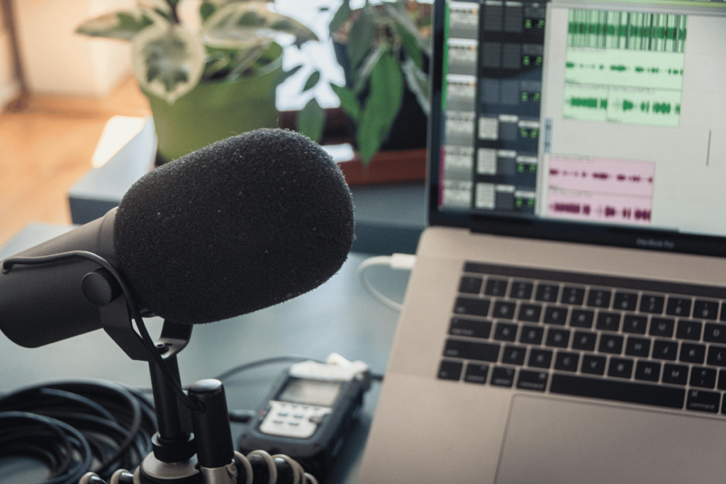 Podcast recording environment with professional microphone and laptop displaying sound waves.