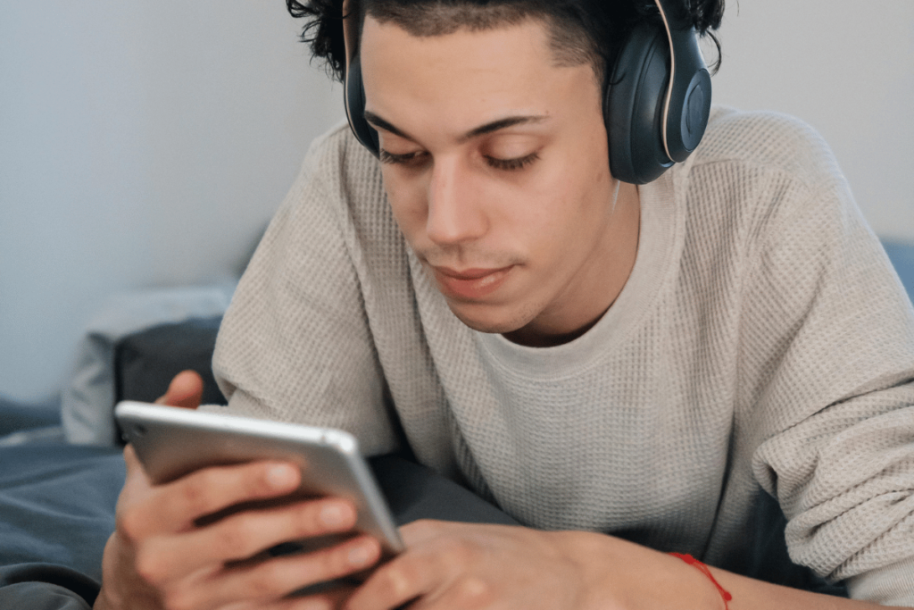 Young man with headphones using a smartphone, enjoying digital entertainment at home.