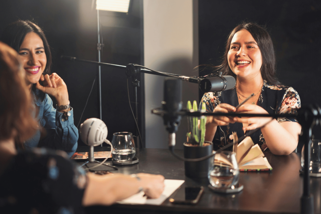 Two women laughing during a lively podcast recording session.