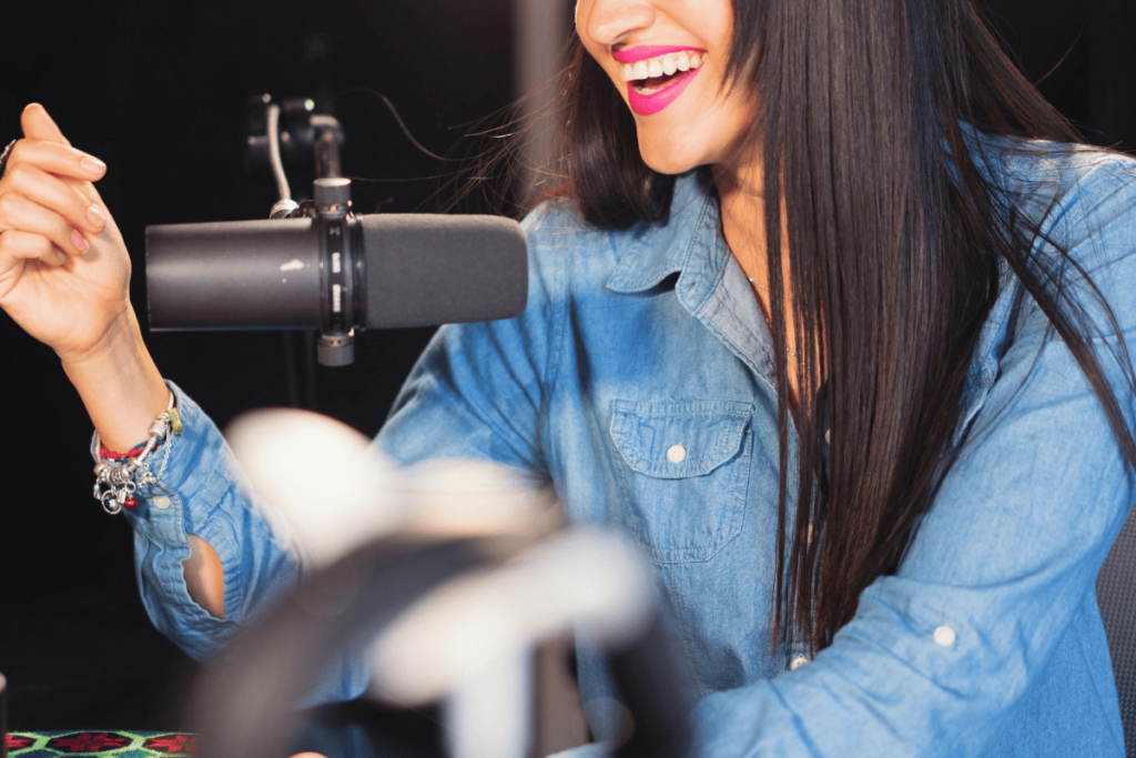 Joyful woman recording a podcast with a professional microphone.