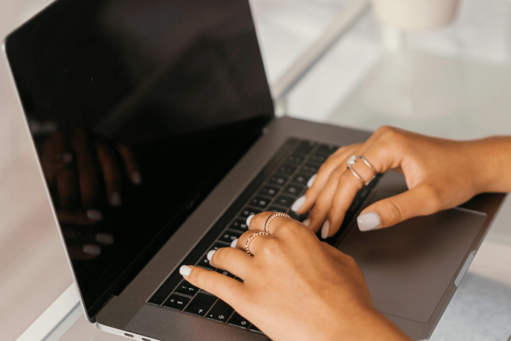 A woman sitting at a desk typing on a laptop computer.