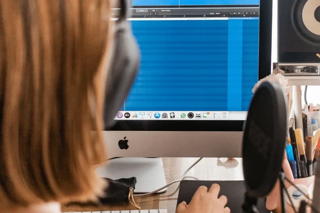 Person recording podcast with microphone and editing software.