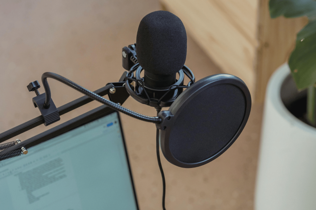 Close-up of a professional podcast microphone with a pop shield attached to a desk.