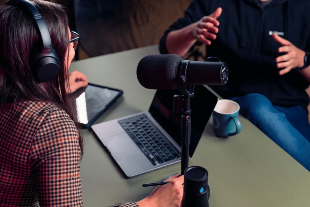 Podcasters recording an episode with a professional microphone and laptop.