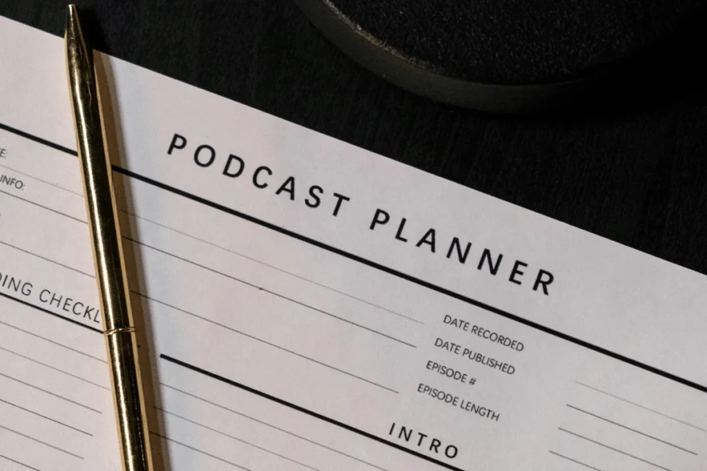 Close-up of a podcast planner sheet with a gold pen, ready to be filled with recording details and episode information.