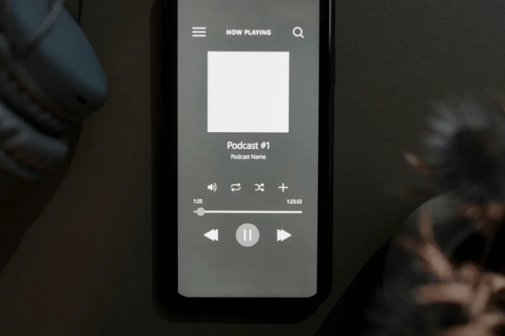 Smartphone displaying a podcast app interface, with headphones in the background.