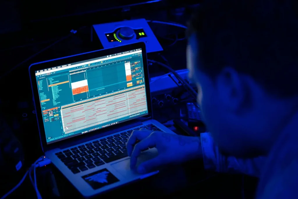 Music producer editing tracks in Ableton Live on a laptop.