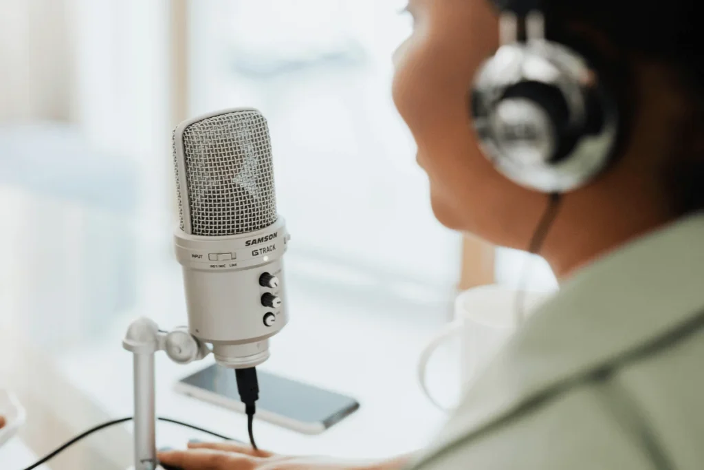 Person speaking into a Samson G-Track microphone while wearing headphones.