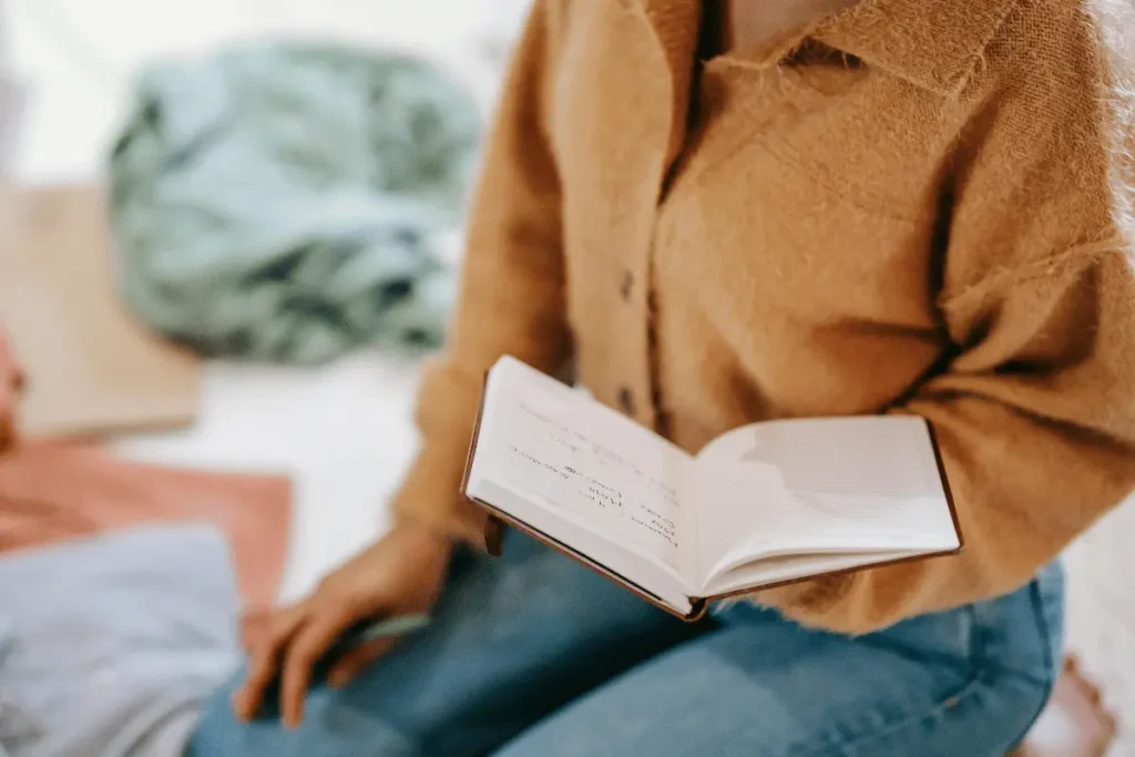 Individual reading a notebook with handwritten notes.