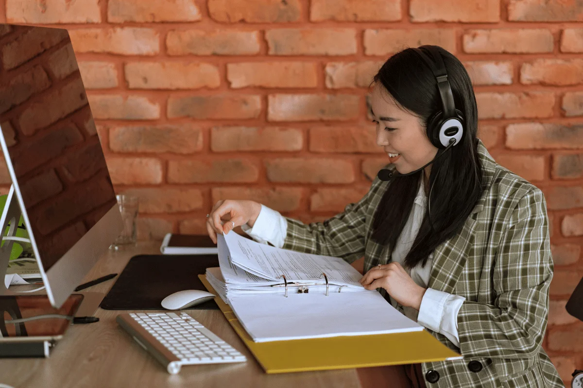 Engaged female employee with headset reviewing documents.