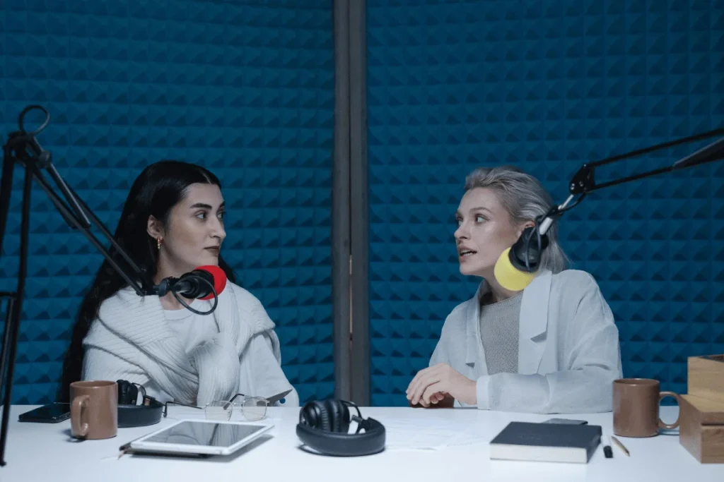 Podcast recording in action with female hosts discussing in a blue studio.