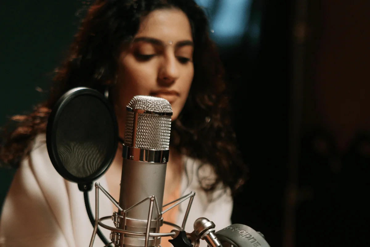 Female artist singing into studio microphone.