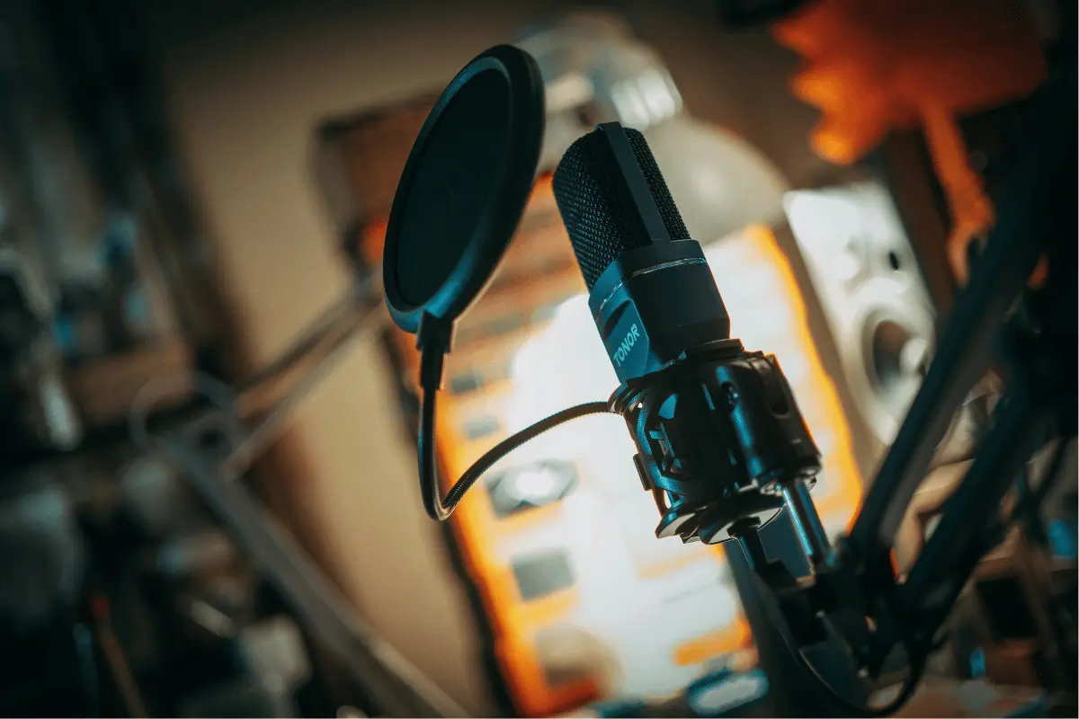 Close-up of a studio microphone with a pop filter in a recording setup.