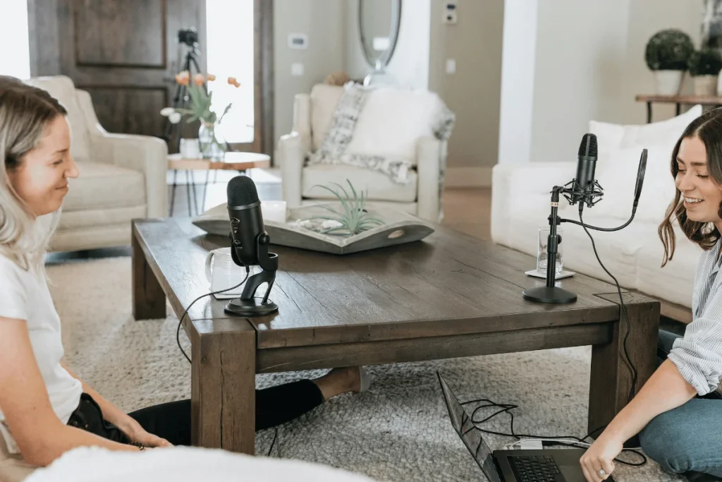 Two women recording a podcast in a living room.