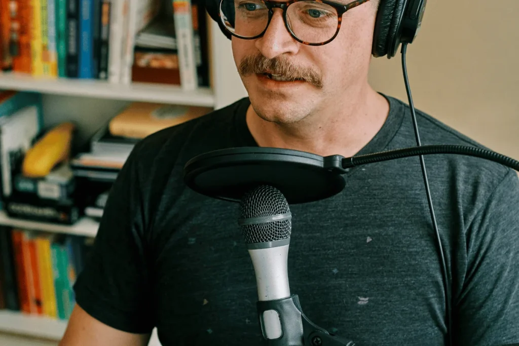 Man with headphones speaking into microphone.