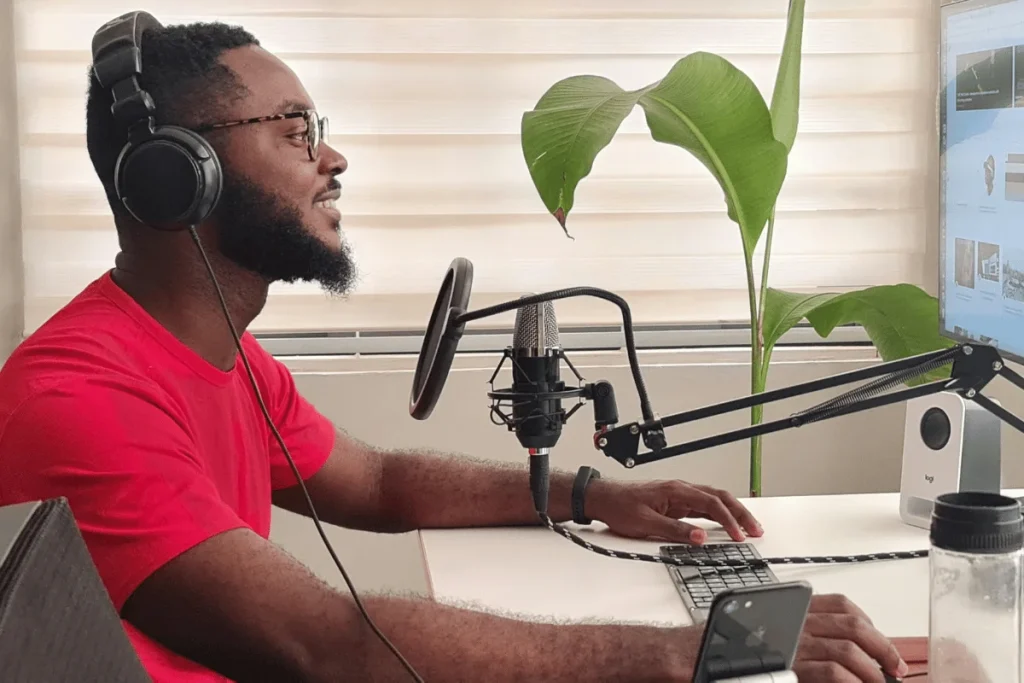 Content creator or podcaster at a desk with microphone and computer setup, ready for recording.