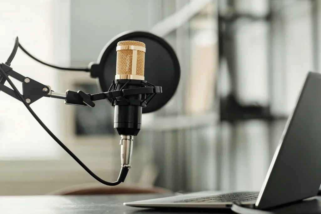 Professional podcast microphone with a laptop in the background.