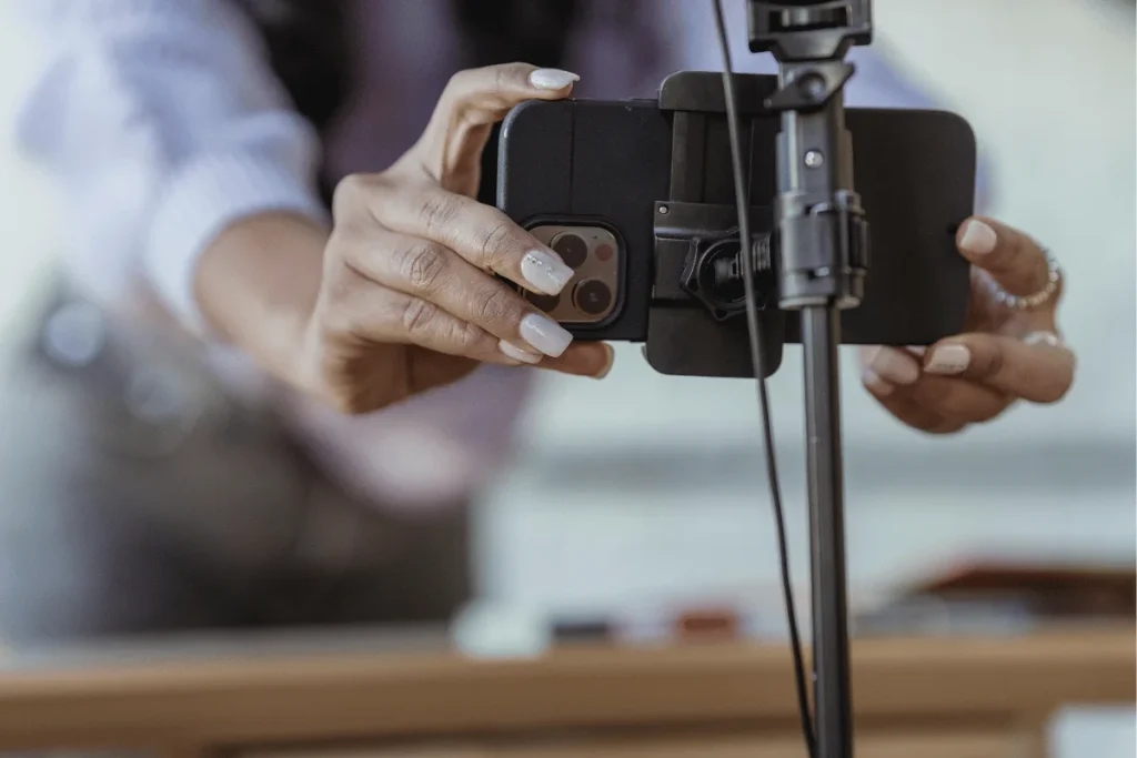 Close-up of hands adjusting a smartphone on a tripod for recording.