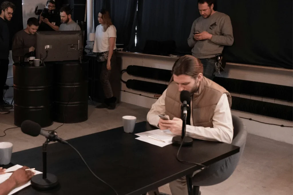 Podcast studio behind the scenes with crew and guest preparing.