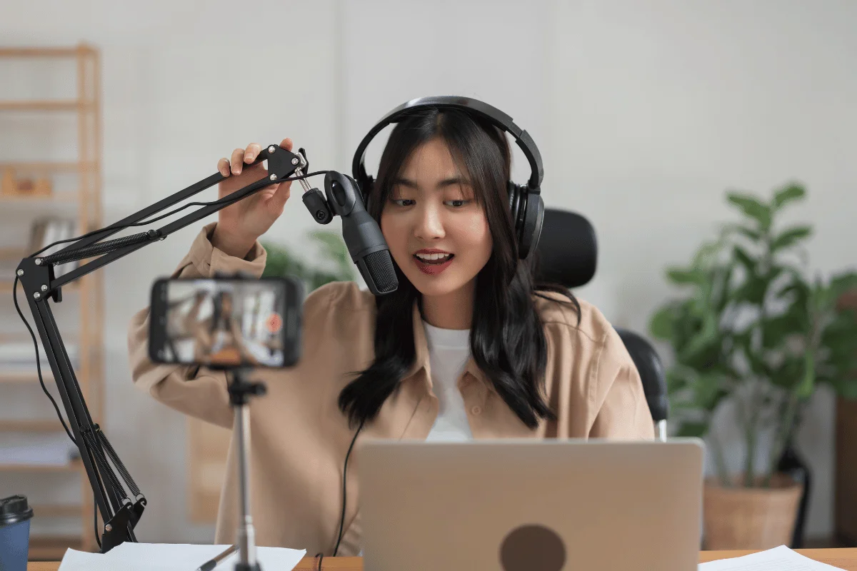 Female podcaster recording a show with a microphone and headphones.