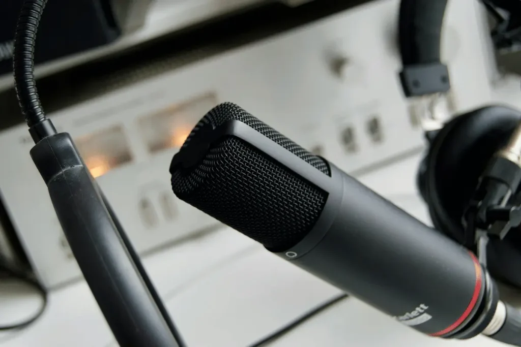 Professional recording microphone with headphones in the background.