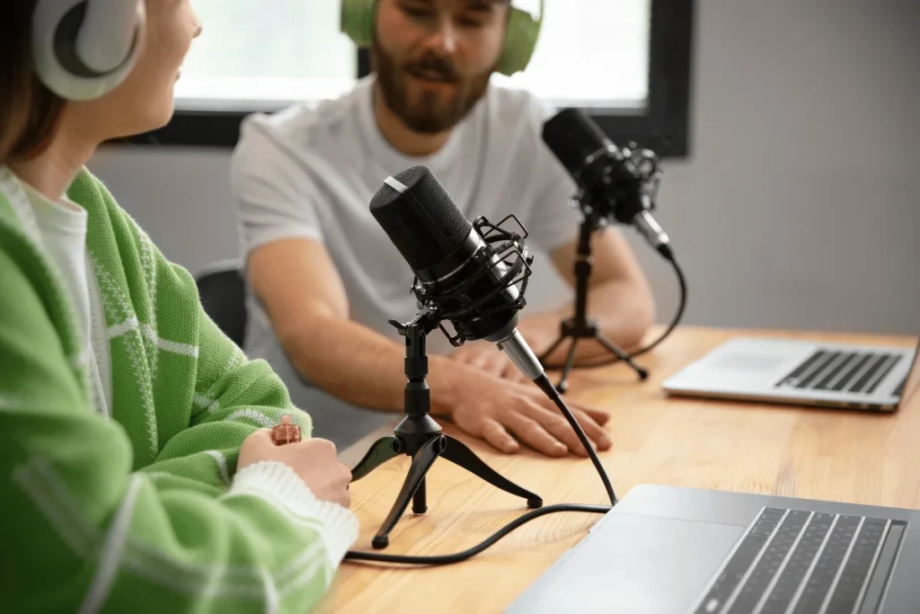 Two people recording a podcast with microphones and laptops.