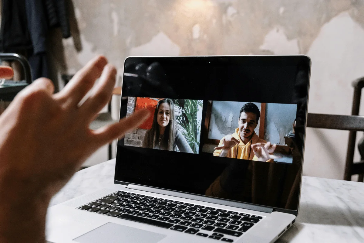 Laptop on a table showing a video call with three participants.