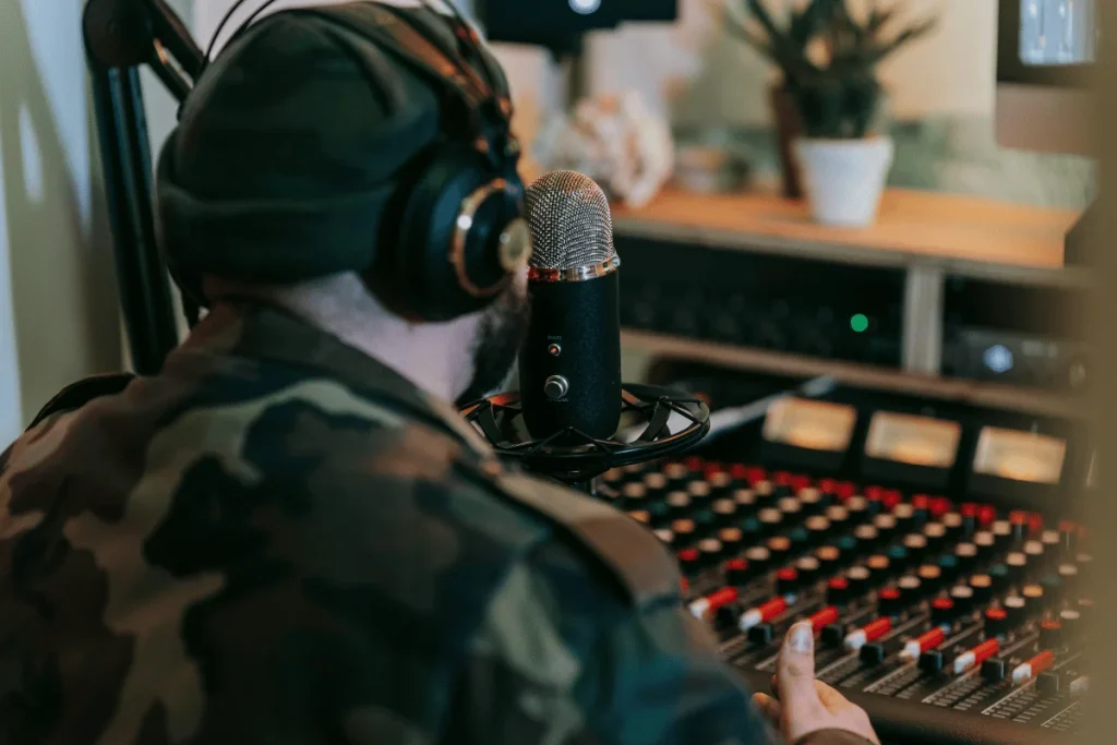 Audio engineer using soundboard and studio mic.