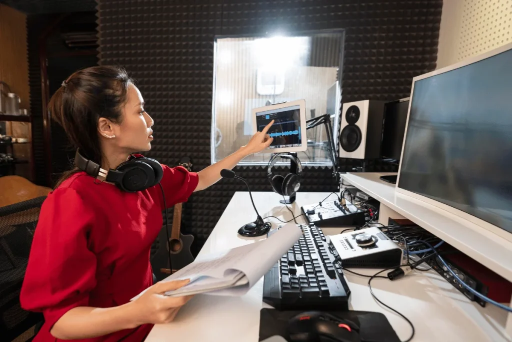 Woman editing audio in a podcast studio with soundproof walls.